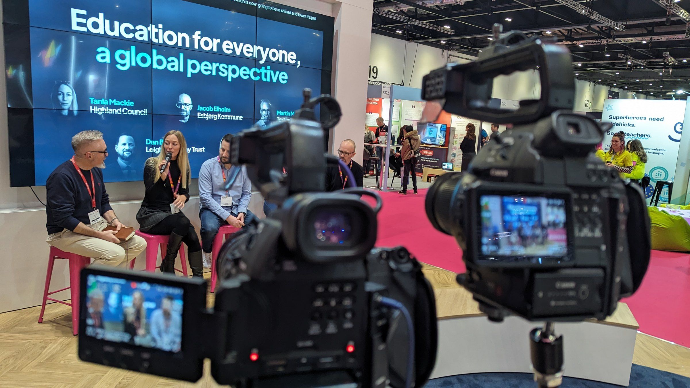 Two Captive8 cameras filming a panel discussion on an exhibition stage